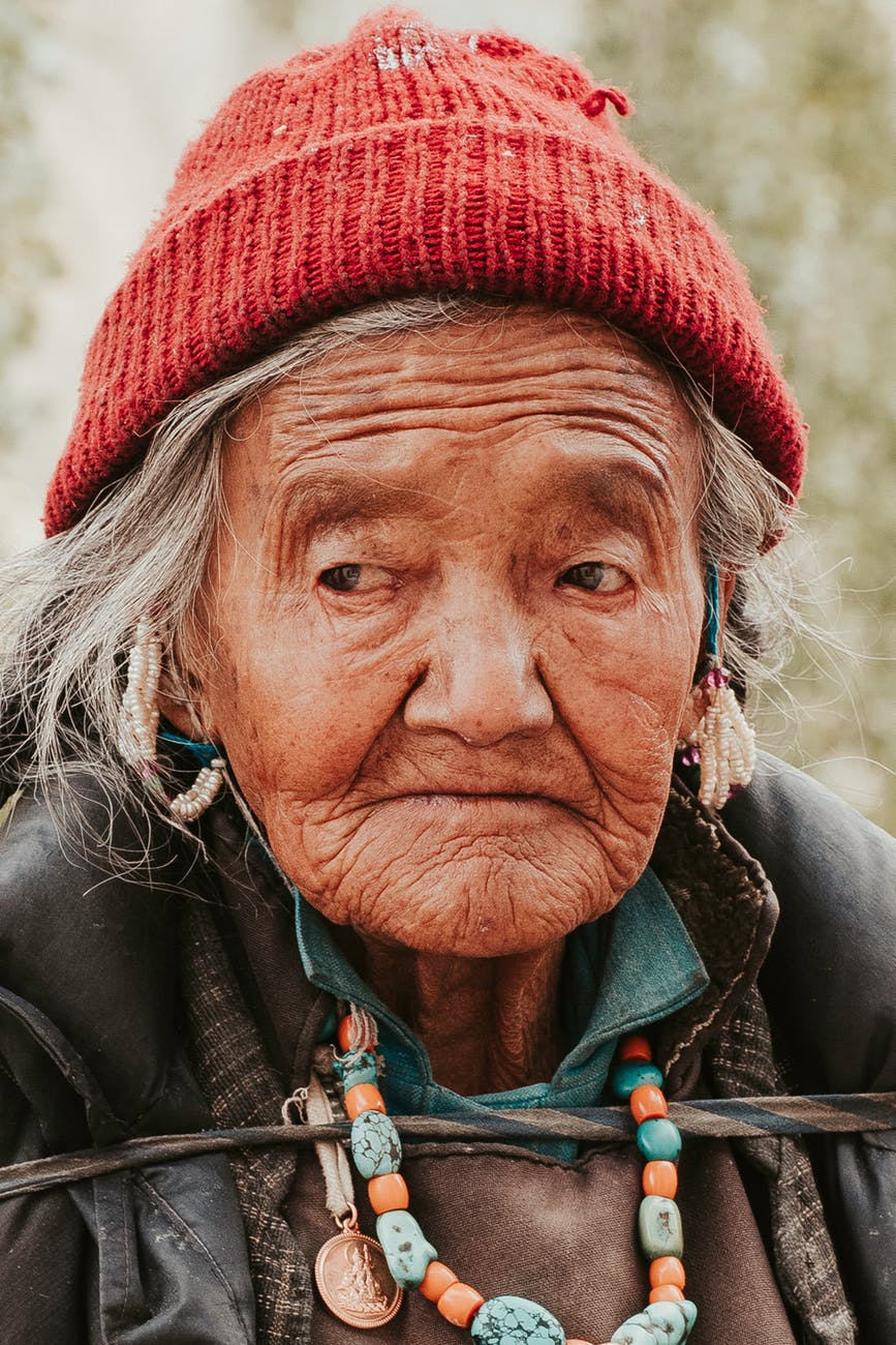 close up photo of an old woman wearing red knit cap